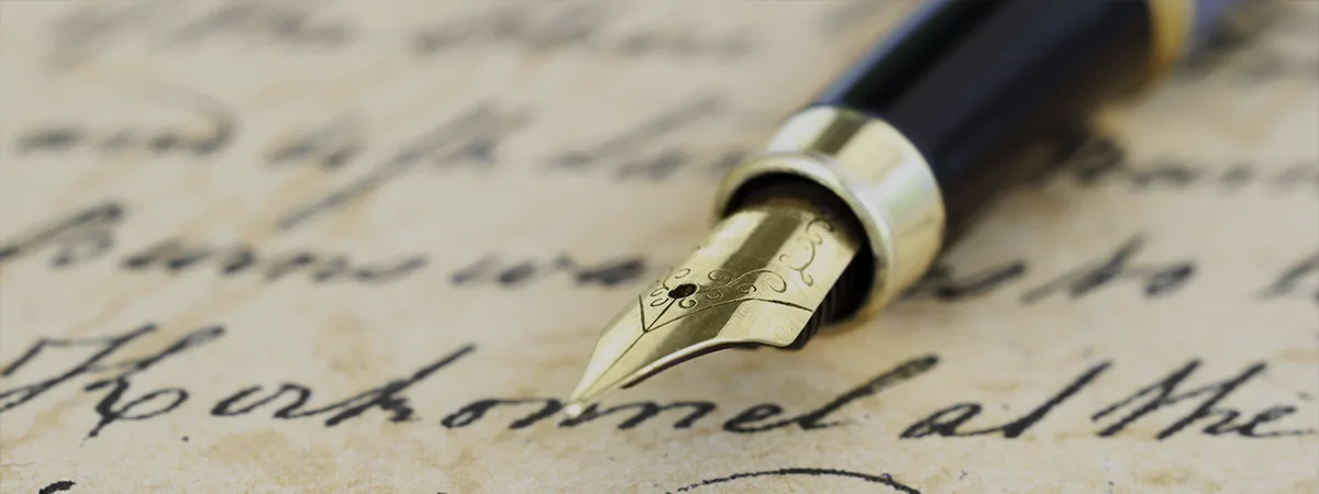 Plume de stylo posée sur une page manuscrite, symbole d’écriture de biographie et de récits de vie