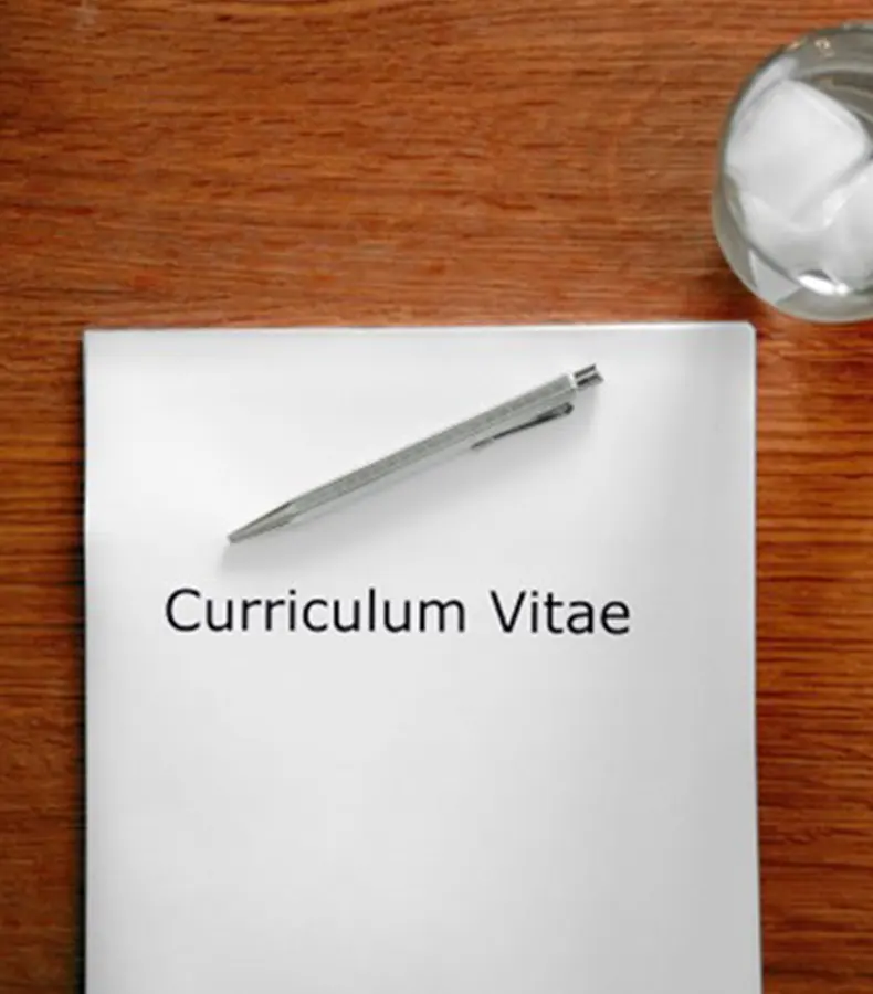 difficile-rediger-cv-lettre-motivation-parcours-professionnel Feuille de Curriculum Vitae avec stylo posé sur un bureau en bois – difficulté à rédiger son parcours professionnel<br />